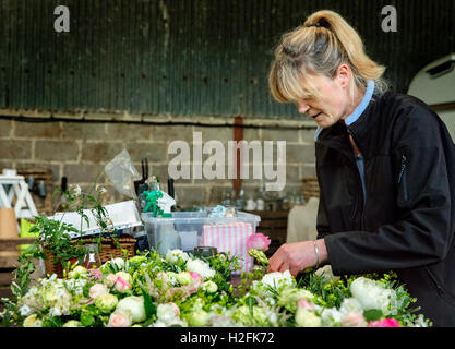 L'arrangement floral commercial. Fleuriste une femme travaillant dans une décoration de table sur le banc et arrangements floraux. Banque D'Images