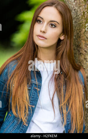 Portrait d'une belle jeune fille triste réfléchie ou femme aux cheveux rouges portant un t-shirt blanc et jeans denim jacket le Banque D'Images