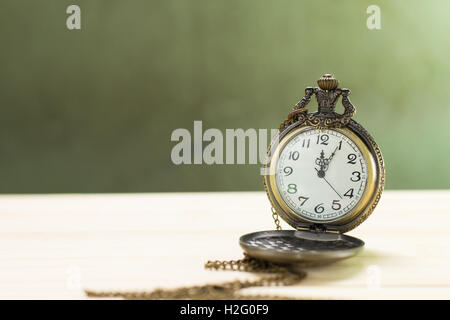 Horloge ancienne sur le plancher en bois et mur vert Arrière-plan. Banque D'Images