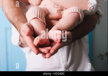 Papa holding newborn fille. Père's hands holding et montrant son bébé âgé de six mois. Pieds de bébé dans les mains du père. Banque D'Images