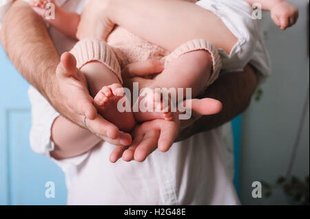 Papa holding newborn fille. Père's hands holding et montrant son bébé âgé de six mois. Pieds de bébé dans les mains du père. Banque D'Images