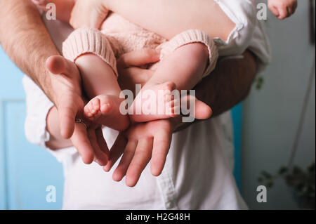 Papa holding newborn fille. Père's hands holding et montrant son bébé âgé de six mois. Pieds de bébé dans les mains du père. Banque D'Images