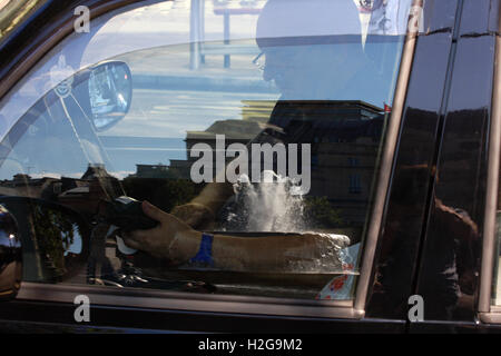 Un chauffeur de taxi de Londres prendre un paiement par carte à Trafalgar Square - un reflet de l'une des fontaines de la porte fenêtre. Banque D'Images