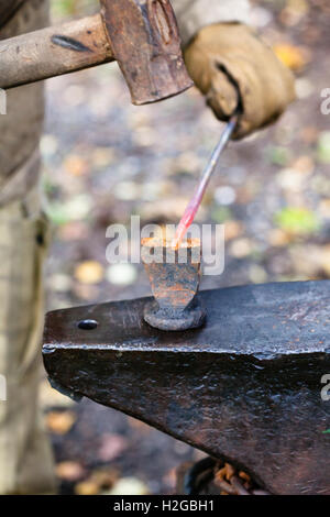 Blacksmith découper le métal chaud rod avec marteau et burin sur enclume dans l'air extérieur forge rurale Banque D'Images