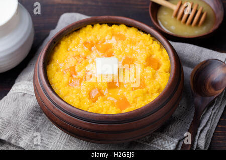 Porridge de millet à la citrouille dans une cuvette d'argile sur un fond de bois rustique. Banque D'Images