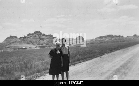 Ville inconnue, United States - 01 janvier 1950 : deux femmes se tenir près d'une route, avec mesasthématiques visible à l'arrière-plan, dans le sud-ouest américain, 1950 Banque D'Images