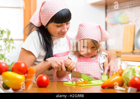 L'enseignement de mère en fille enfant cuisine en salade. Maman et enfant hacher les légumes sur une planche à découper avec couteau. La cuisson conc Banque D'Images