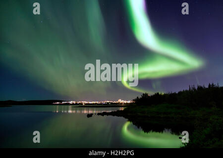 Les Aurora plus Eillidavatn près de Reykjavik en Islande. eau calme reflétant les aurores boréales dans le ciel flamboyant. Banque D'Images