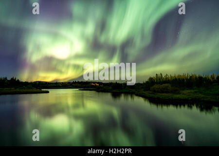 Les Aurora plus Eillidavatn près de Reykjavik en Islande. eau calme reflétant les aurores boréales dans le ciel flamboyant. Banque D'Images