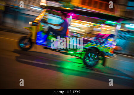 Un classique de taxi tuk-tuk motorisé par un zoom avant dans un flou de néons de nuit à Bangkok, Thaïlande Banque D'Images