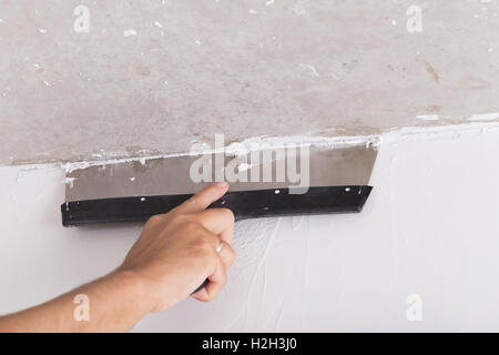 Chambre par l'amélioration de la couche de finition travailleur met en stuc sur le mur à l'aide d'une truelle de plâtrage Banque D'Images
