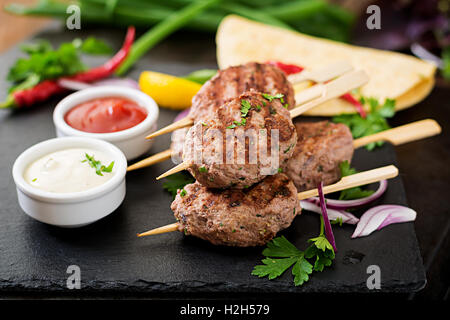 Kofta délicieux kebab (boulettes) avec la sauce et les tacos tortillas sur fond noir Banque D'Images