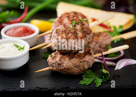 Kofta délicieux kebab (boulettes) avec la sauce et les tacos tortillas sur fond noir Banque D'Images