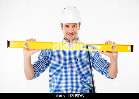 Heureux jeune homme builder dans la construction d'helmet holding spirit level Banque D'Images