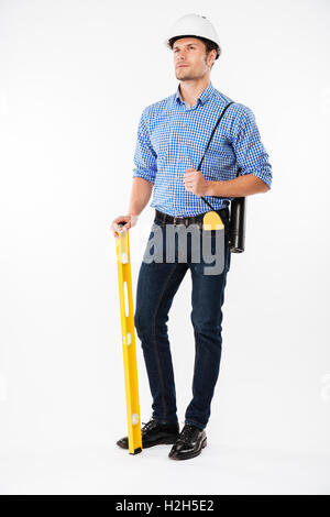 Jeune homme pensif dans le bâtiment de l'architecte helmet holding niveau de l'esprit et la pensée Banque D'Images