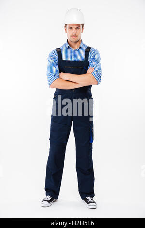 Toute la longueur du jeune homme confiant contremaître dans helmet standing with arms crossed Banque D'Images