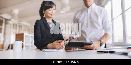 Shot of young business people appareil au bureau. Deux jeunes gens à l'aide d'un écran tactile à l'ordinateur de bureau moderne Banque D'Images