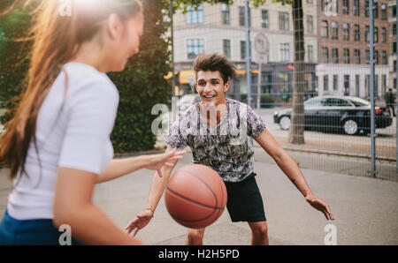 Deux jeunes homme et femme jouant au basket-ball sur une cour. Amis, pour avoir un match de basket-ball. Banque D'Images