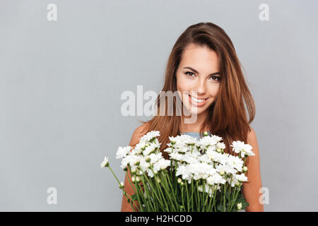 Gros plan du cheerful attractive young woman with bouquet de fleurs sur fond gris Banque D'Images