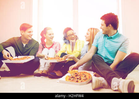 Cinq adolescents souriants de manger une pizza à la maison Banque D'Images