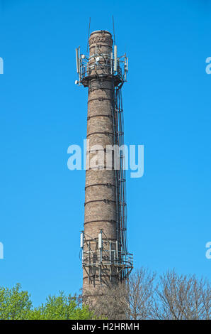 Cheminée en brique avec des répéteurs connectés dans une zone industrielle sur le fond de ciel Banque D'Images