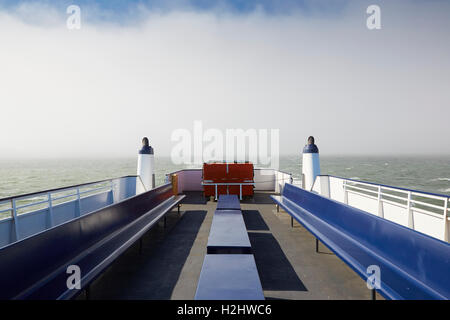 Ferry bleu et or passe par un banc de brouillard en route à Pier 41, San Francisco, Californie. Banque D'Images