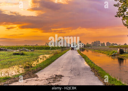 Piste sur route de terre près de canal d'irrigation dans la campagne italienne Banque D'Images