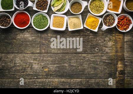 Diverses herbes et épices séchées dans des bols en céramique sur la vieille table en bois. Vue d'en haut. Banque D'Images