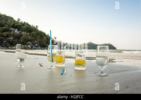 La pollution sur la plage. Danger ! Broken bière et d'alcool avec de la paille de verre laissés dans le sable Banque D'Images