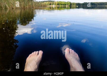 Jambes et Pieds dans l'eau du lac Clear set contre été belle vue paysage modèle libération : Oui. Biens : Non. Banque D'Images