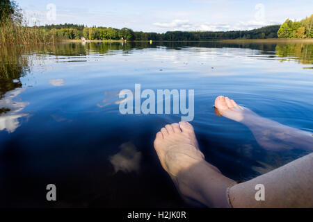 Jambes et Pieds dans l'eau du lac Clear set contre été belle vue paysage modèle libération : Oui. Biens : Non. Banque D'Images