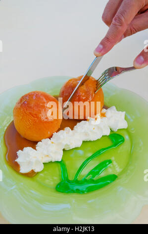 Dessert : deux pêches au four avec de la crème chantilly, sauce caramel et menthe poivrée. Voir de très près. Banque D'Images