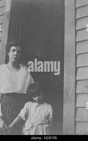 Ville inconnue, United States - 01 janvier 1953 : Mère et fille aux portes d'une maison, 1953. La mère tient la main de sa fille, et la fille semble timide. Banque D'Images