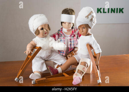 Trois poupées assis, des bandages sur la tête, la jambe d'une attelle, béquilles, oeil de patchs, Armverband, épaule bandage et luxe Banque D'Images