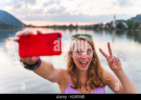 Jeune femme prenant, selfies à rire et signe la paix, Schliersee, Haute-Bavière, Bavière, Allemagne Banque D'Images