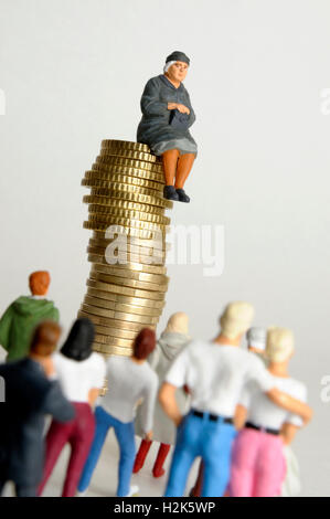 Une femme âgée, figurine, assis sur pile de pièces, suivi par d'autres, image symbolique pour l'héritage Banque D'Images