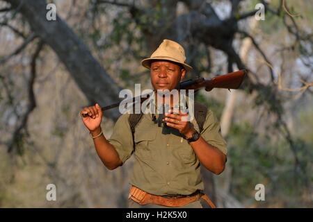 Guide avec des jumelles et un fusil sur un safari à pied, Mana Pools National Park, Zimbabwe, Province Mashonaland Ouest Banque D'Images