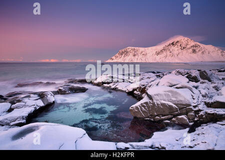 Alpenglow sur la plage rocheuse de Skagsanden sur les îles Lofoten en Norvège du Nord, photographié au crépuscule en hiver. Banque D'Images