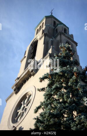 Vue spectaculaire vue sur clocher de l'église clocher, vitrail rond et croix avec arbre en premier plan Banque D'Images