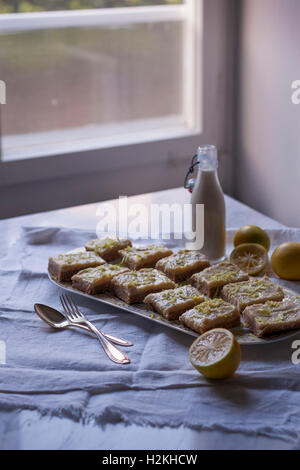 Matières et de noix de coco carrés au citron pour deesert sur un plat de service, parsemer de zestes de citron Banque D'Images