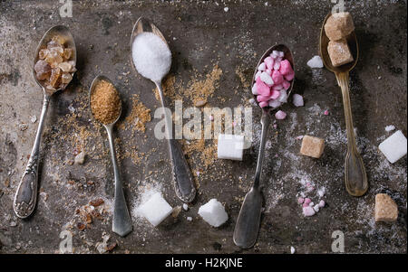 Cuillères vintage différents avec variété de sucre blanc, brun rose fruit de granules, de cubes et de cristal vieux fer texture backg Banque D'Images