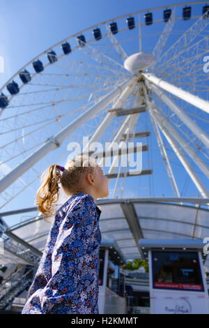 Jolie petite fille ressemble à grande roue contre un ciel bleu à sunny day Banque D'Images