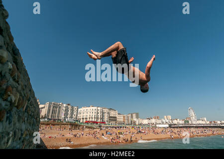 Les jeunes de sauter dans la mer depuis l'épi de banjo sur la plage de Brighton Banque D'Images