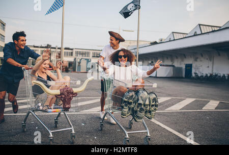 Jeunes amis s'amusant sur un shopping trolleys. Les jeunes multiethniques racing sur panier. Banque D'Images