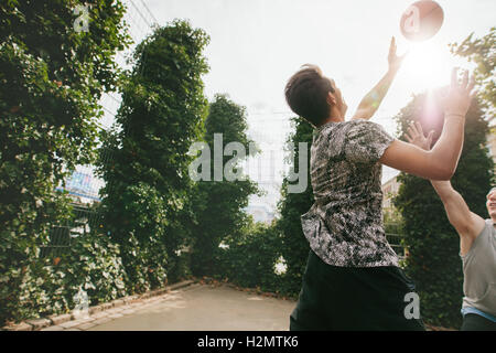 Les amis jouant au basket-ball l'un contre l'autre et s'amuser sur une cour. Deux jeunes hommes jouant au basket-ball sur une journée d'été. Banque D'Images