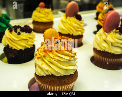 Cupcakes colorés sur un écran en pâtisserie boutique Banque D'Images