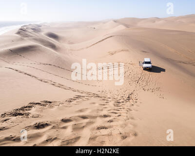 Une voiture de quatre par quatre sur les dunes du désert du Namib dans la région de Sandwich Harbour, la Namibie. L'orientation horizontale, grand angle. Banque D'Images