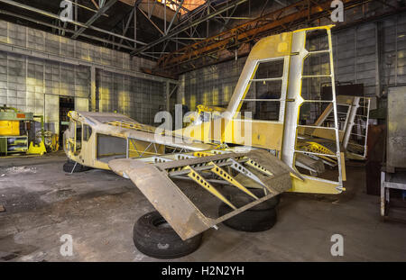 L'usine d'aviation abandonné de petits avions. L'aéronef de construction en partie dans un bâtiment industriel sombre dans la nuit. Banque D'Images