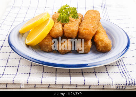 Poissons frits collés fabriqués à partir de poissons Lieu de l'Alaska dont la tranche de citron et le persil dans une assiette Banque D'Images