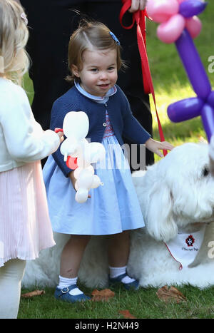 La princesse Charlotte joue avec un chien nommé Moose à une fête pour les enfants à une fête pour les enfants pour les familles des militaires à l'Hôtel du Gouvernement à Victoria au cours de la tournée royale du Canada. Banque D'Images